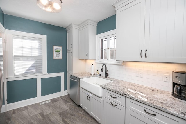 kitchen featuring a sink, tasteful backsplash, stainless steel dishwasher, and light stone counters