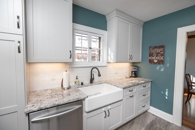 kitchen featuring light stone countertops, baseboards, a sink, dishwasher, and backsplash