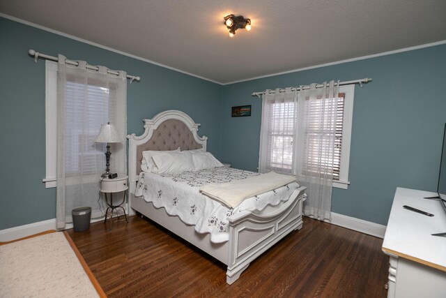 bedroom with crown molding, dark wood-style floors, and baseboards