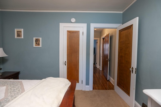 carpeted bedroom featuring a closet, crown molding, and baseboards