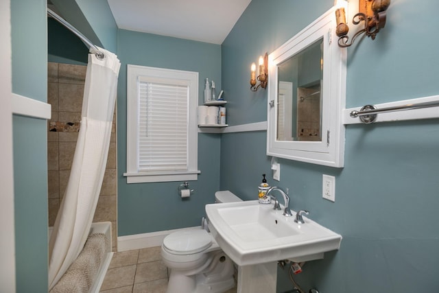 bathroom featuring baseboards, shower / bath combo, a sink, tile patterned flooring, and toilet