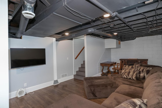 living room with visible vents, baseboards, stairway, wood finished floors, and concrete block wall