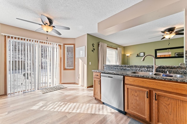 kitchen featuring dark countertops, light wood-style flooring, brown cabinetry, a sink, and dishwasher