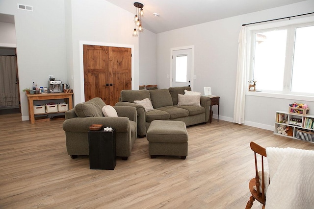 living room with high vaulted ceiling, light wood-style flooring, visible vents, and baseboards