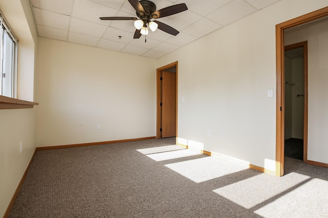 carpeted spare room with a ceiling fan, baseboards, and a drop ceiling