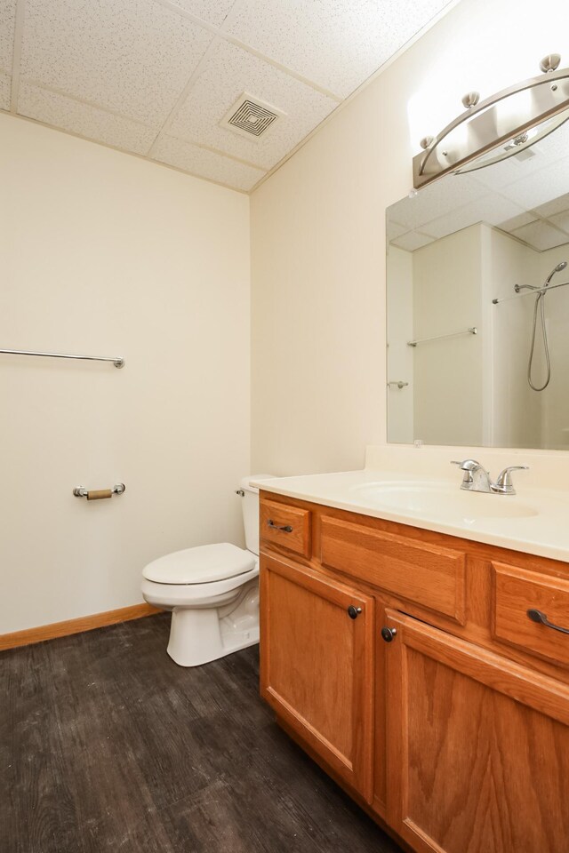 full bathroom with a paneled ceiling, visible vents, toilet, vanity, and wood finished floors