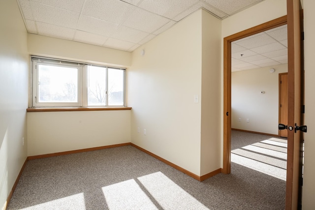 carpeted empty room with a paneled ceiling and baseboards