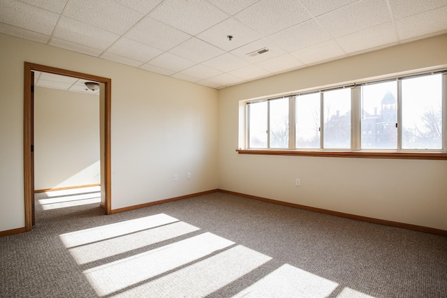 unfurnished room with carpet floors, a drop ceiling, visible vents, and baseboards