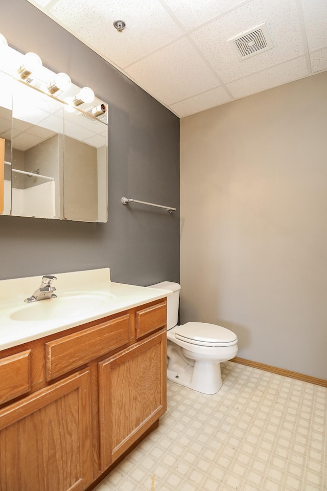 bathroom featuring visible vents, vanity, a drop ceiling, baseboards, and tile patterned floors