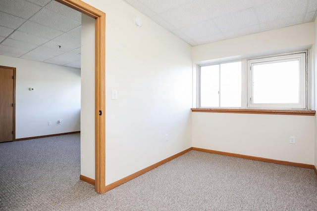 spare room with carpet floors, a drop ceiling, and baseboards