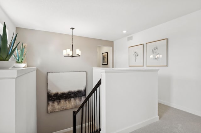 hallway featuring visible vents, an inviting chandelier, carpet flooring, an upstairs landing, and baseboards