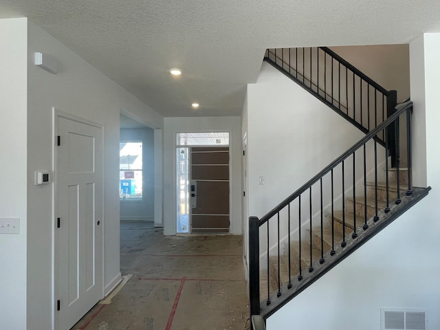 foyer entrance featuring stairway, visible vents, a textured ceiling, and recessed lighting