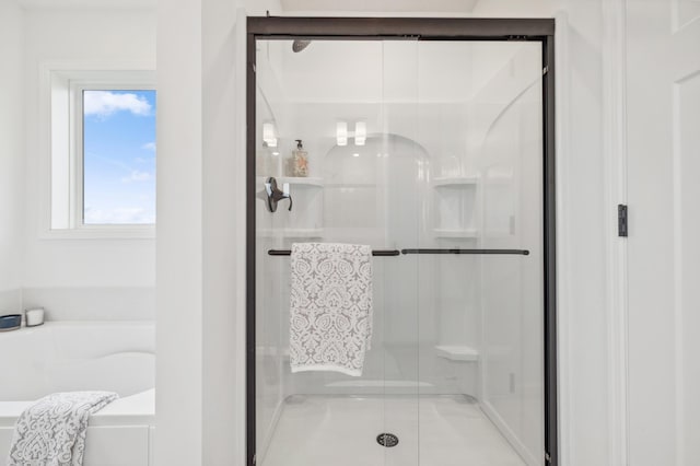 bathroom featuring a shower stall and a bath