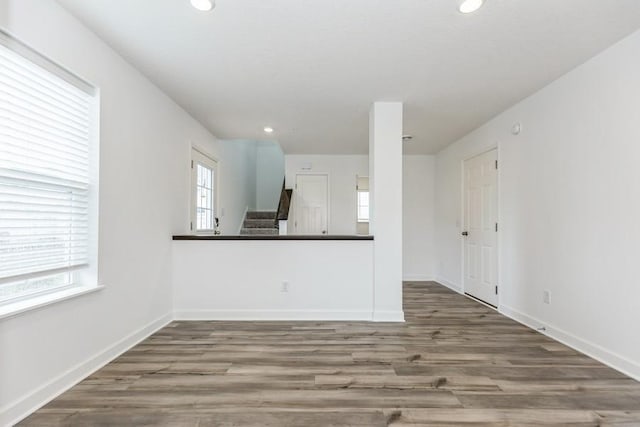 unfurnished living room with recessed lighting, stairway, baseboards, and wood finished floors