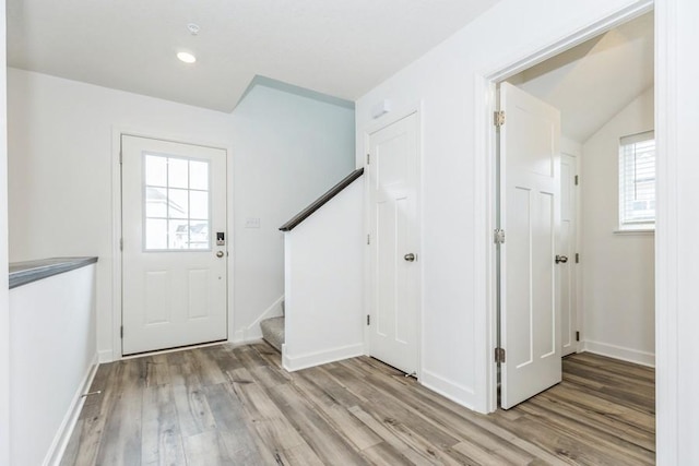 foyer entrance featuring light wood-style floors, stairs, and a wealth of natural light