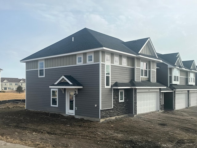 exterior space featuring board and batten siding, an attached garage, and a shingled roof