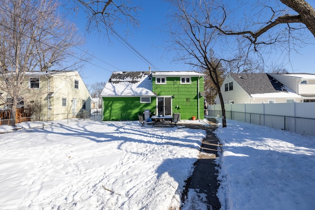 snow covered house featuring a residential view and a fenced backyard