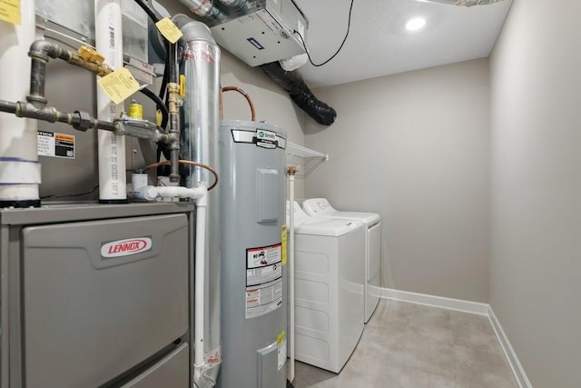 laundry room with baseboards, washing machine and dryer, water heater, laundry area, and heating unit