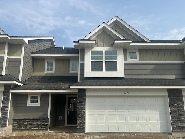 view of front of house featuring a garage, board and batten siding, stone siding, and a shingled roof