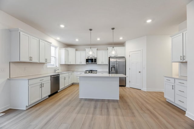 kitchen with light wood finished floors, light countertops, backsplash, appliances with stainless steel finishes, and a sink