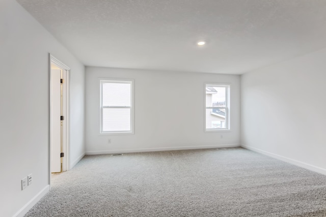 spare room featuring carpet floors, a healthy amount of sunlight, baseboards, and recessed lighting