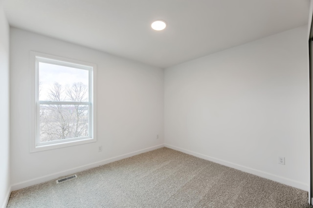 carpeted spare room featuring visible vents and baseboards