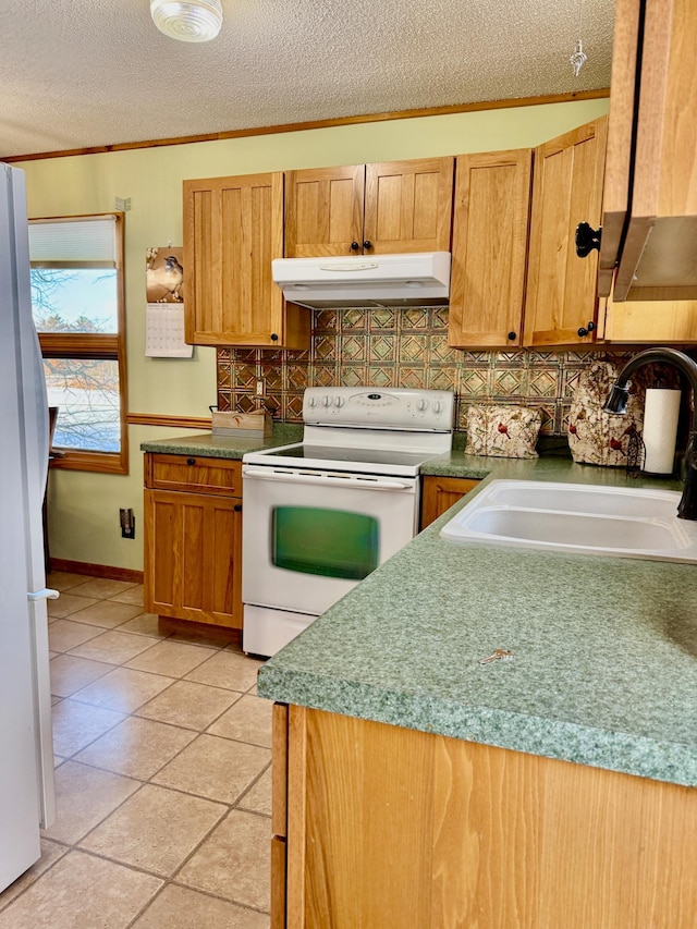 kitchen featuring a textured ceiling, under cabinet range hood, white appliances, a sink, and backsplash