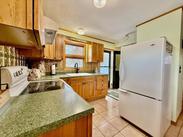 kitchen featuring white appliances, brown cabinetry, a sink, backsplash, and light tile patterned flooring