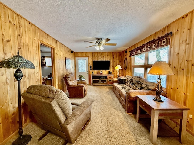 carpeted living room featuring ceiling fan, a textured ceiling, and wooden walls