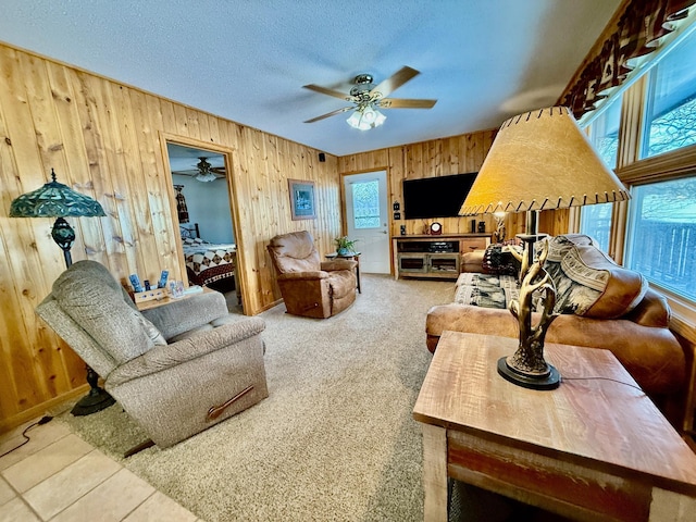 living room with wood walls, ceiling fan, and a textured ceiling