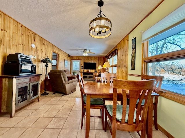 dining area featuring a healthy amount of sunlight, wood walls, light tile patterned floors, and a textured ceiling