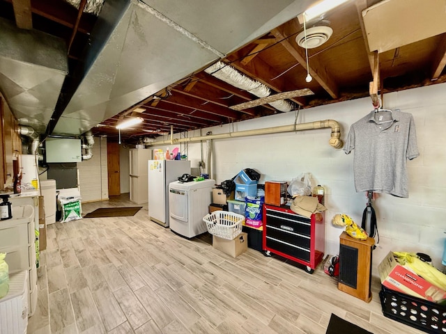 unfinished below grade area featuring washing machine and clothes dryer, wood finished floors, and freestanding refrigerator