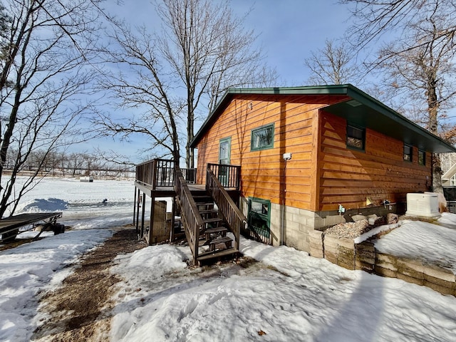 view of snowy exterior with a deck and stairs