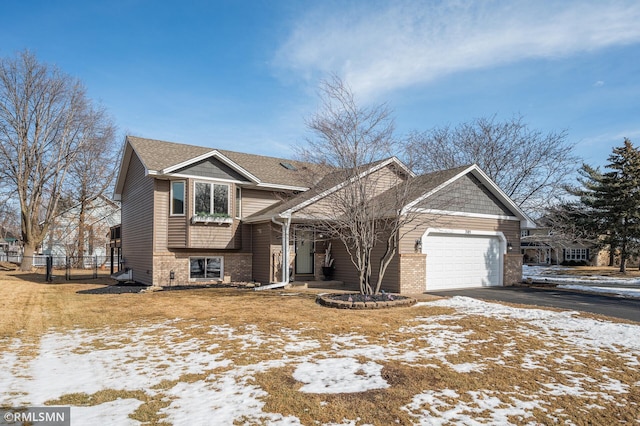 view of front facade featuring aphalt driveway, a garage, brick siding, fence, and roof with shingles