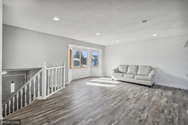 living room with a textured ceiling, baseboards, dark wood-type flooring, and recessed lighting