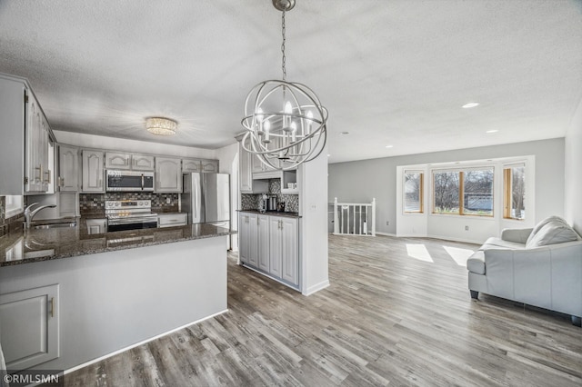 kitchen with open floor plan, stainless steel appliances, a peninsula, and gray cabinets