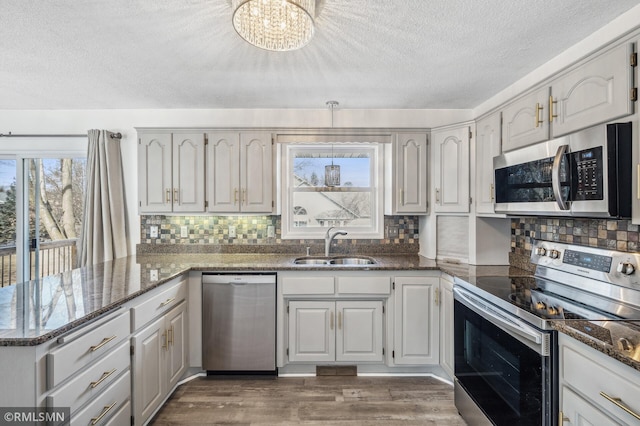 kitchen with a peninsula, plenty of natural light, white cabinets, and stainless steel appliances