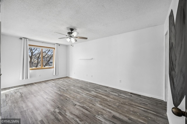 spare room with dark wood-style flooring, ceiling fan, a textured ceiling, and baseboards