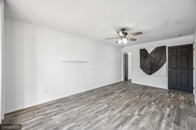 unfurnished living room featuring ceiling fan, a textured ceiling, baseboards, and wood finished floors