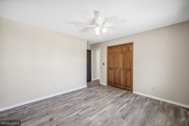 unfurnished bedroom featuring ceiling fan, a closet, light wood-type flooring, and baseboards