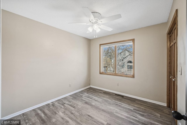 unfurnished bedroom with a closet, a textured ceiling, baseboards, and wood finished floors