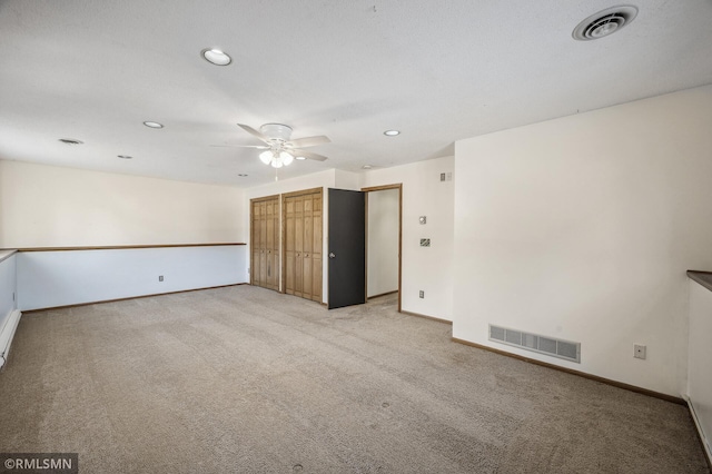 spare room with light carpet, baseboards, visible vents, and ceiling fan