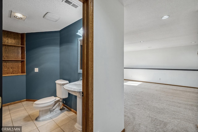 half bathroom with baseboards, visible vents, toilet, tile patterned floors, and a textured ceiling