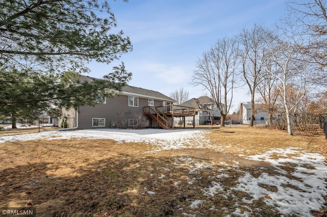 snow covered rear of property with stairs, fence, and a deck