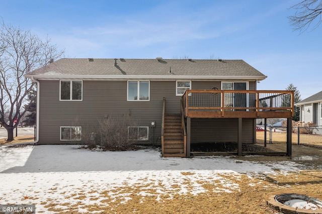 snow covered property featuring a fire pit, a shingled roof, fence, stairs, and a wooden deck