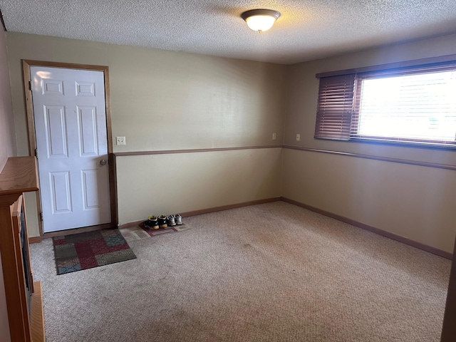 spare room featuring carpet, baseboards, and a textured ceiling