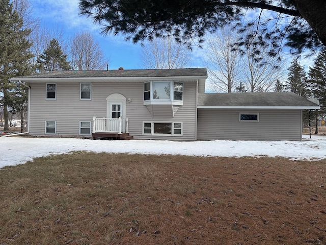 snow covered rear of property featuring a lawn