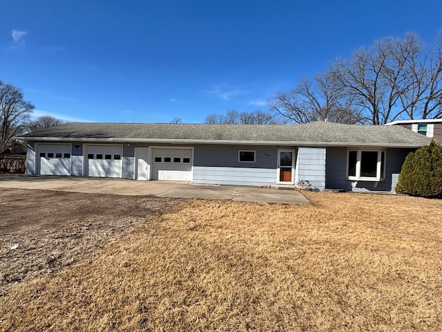 ranch-style house with driveway, an attached garage, a front lawn, and a shingled roof