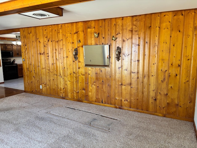 spare room with wooden walls, beam ceiling, light colored carpet, and visible vents