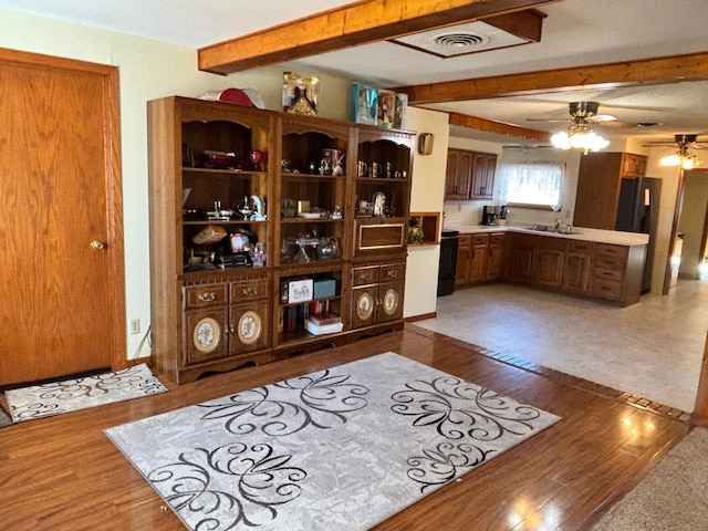 interior space with light countertops, beamed ceiling, and wood finished floors